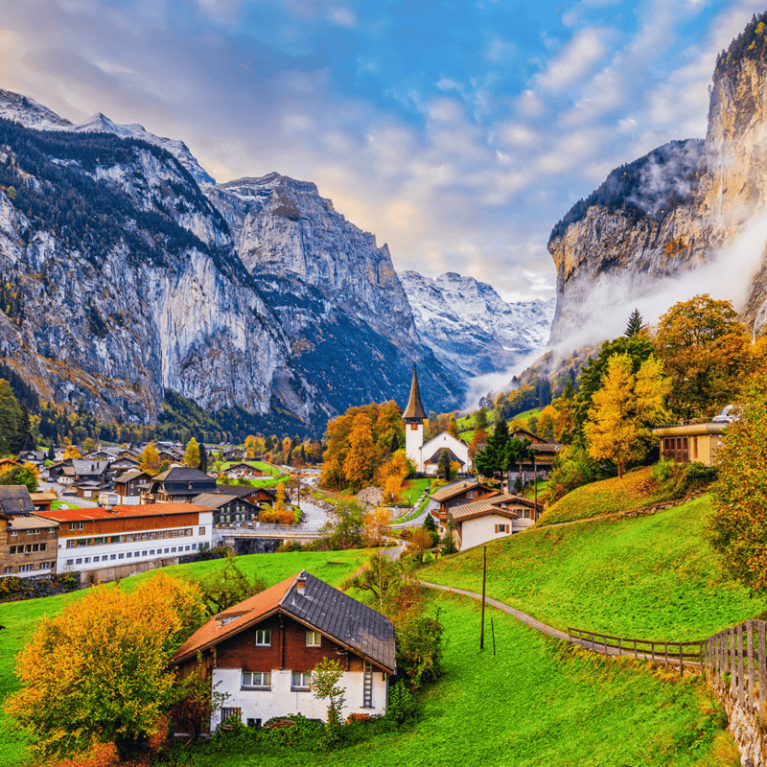 Houses on a green hill with snowy mountains in the background in Lauterbrunnen, Switzerland
